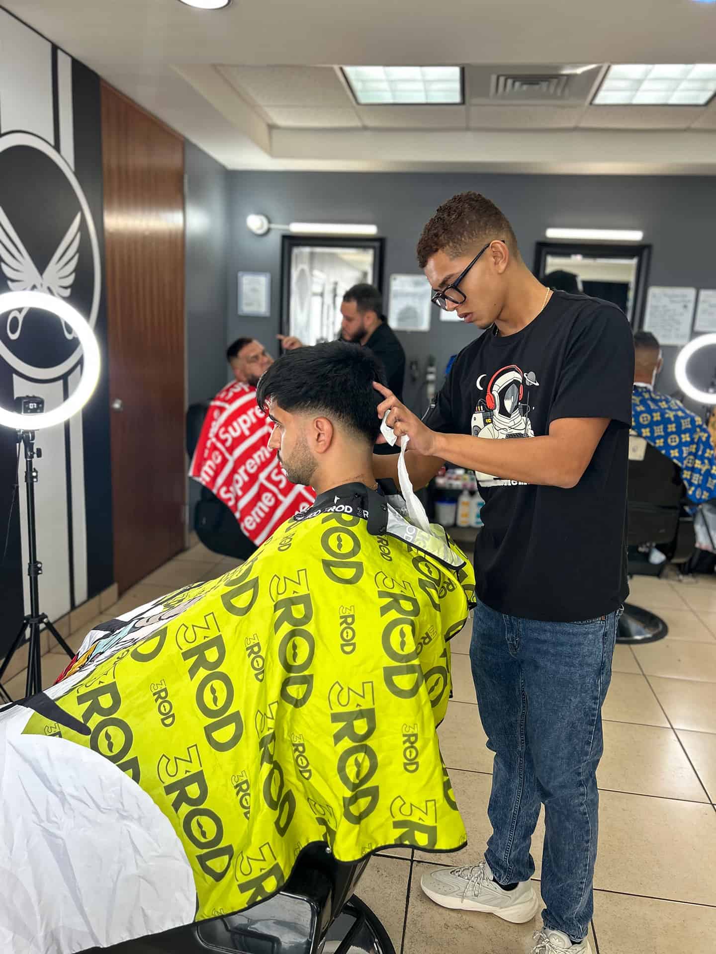 Yahir Oscar recortando a un cliente en la barberia.